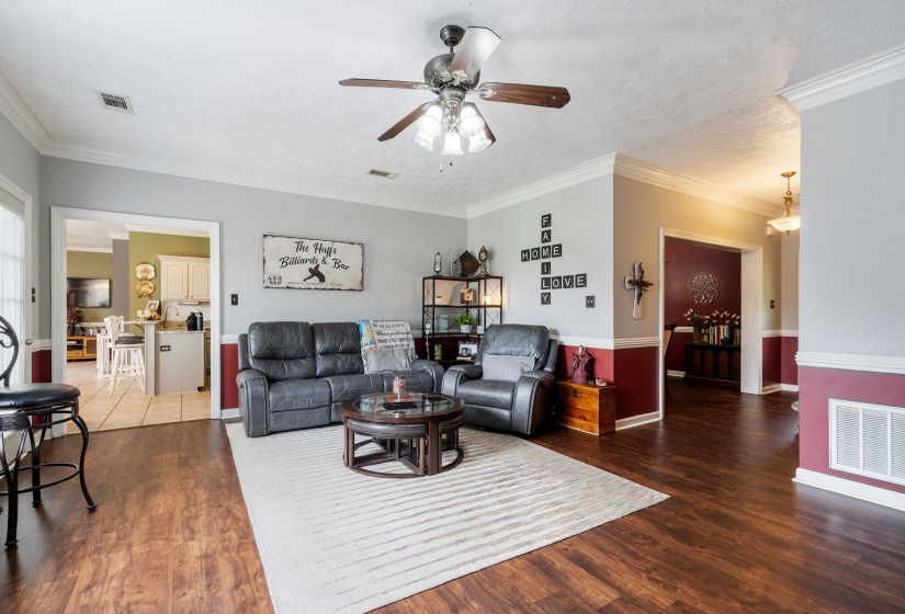 Spacious living area featuring wood-finish flooring, two-tone wall treatment, and crown molding
