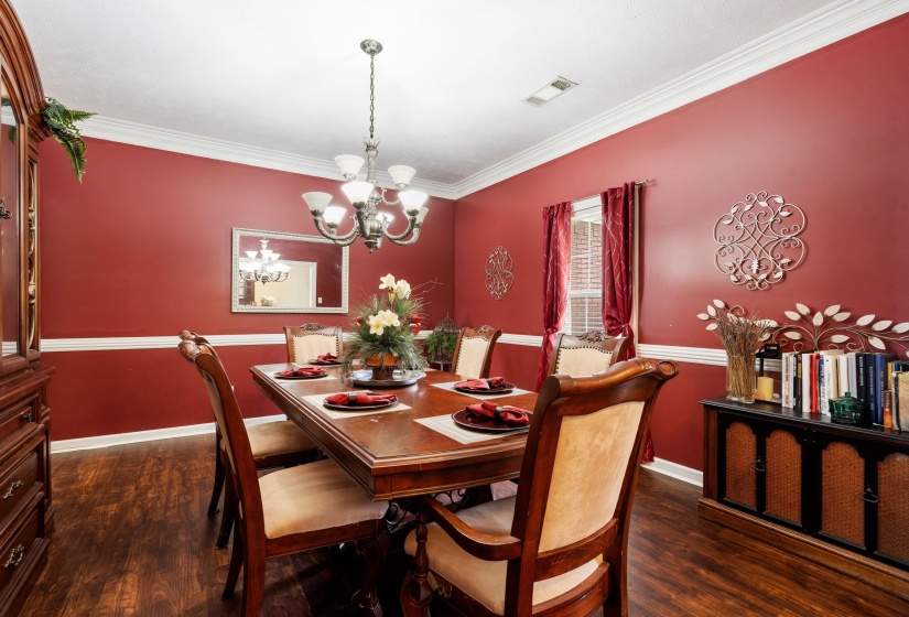 Dining area featuring wood-finish flooring, a white crown molding and chair rail, and a multi-bulb chandelier