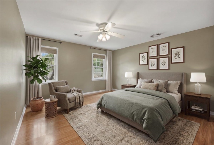 Spacious bedroom featuring light-toned walls, wood-finish flooring, a ceiling fan, and multiple windows