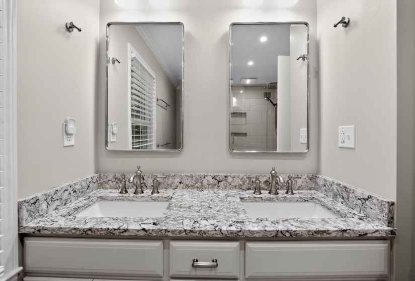 Double vanity featuring undermount sinks, stone-finish countertops, and brushed nickel fixtures