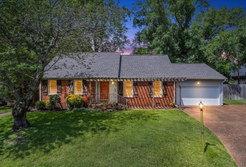 Brick facade home featuring a gabled roof, attached garage, and a covered front entry