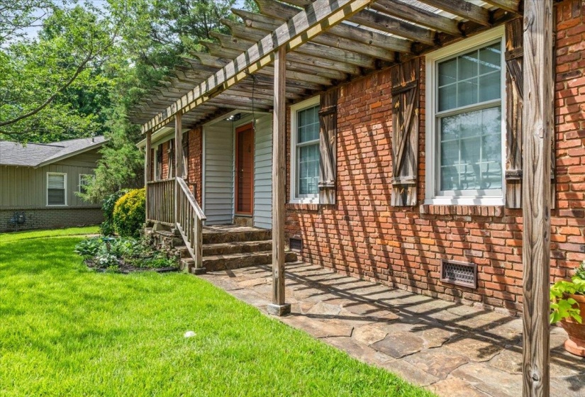 Brick exterior featuring a stone walkway and a wooden pergola structure