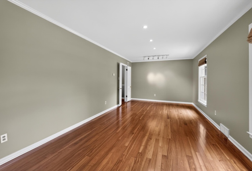 Spacious room featuring wood-finish flooring, recessed lighting, and crown molding