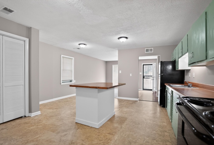 Kitchen featuring green cabinetry, wood-finish countertops, and black appliances