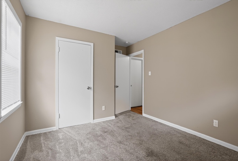 Carpeted interior room featuring neutral wall tones, white trim, and a window with blinds