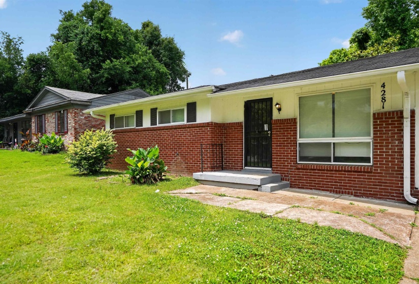 Brick and siding exterior featuring a covered entry with security door, concrete steps, and a large front window