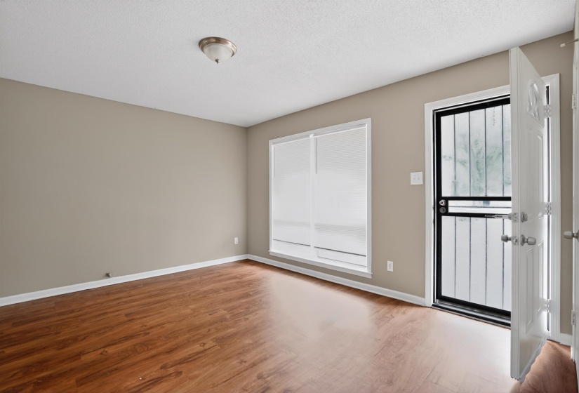 Open entry with a security screen door, wood-finish flooring, and neutral wall tones