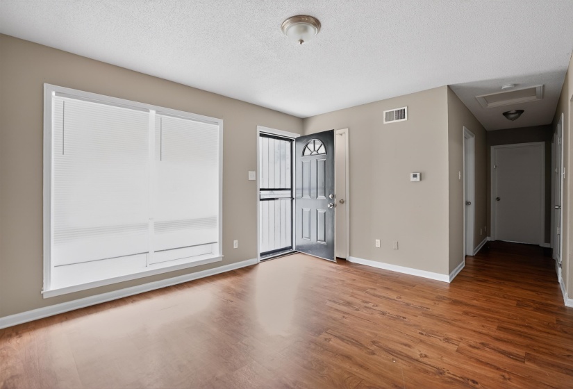 Spacious room featuring wood-finish flooring, neutral-toned walls, and white trim