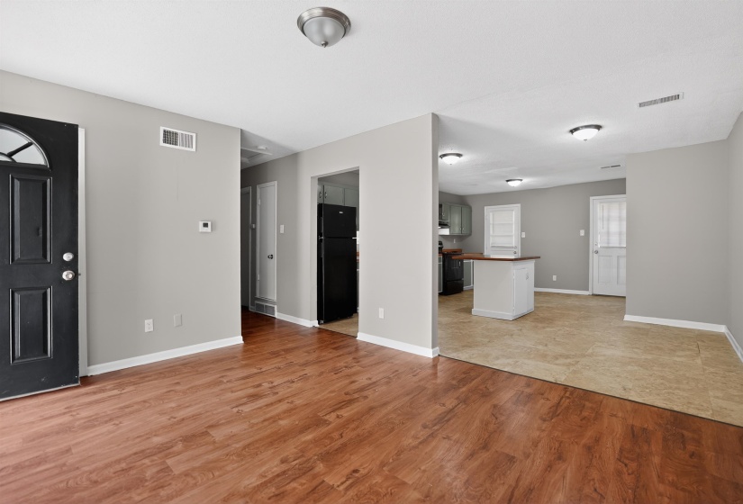 Spacious living area featuring wood-finish flooring, light gray wall paint, and white trim