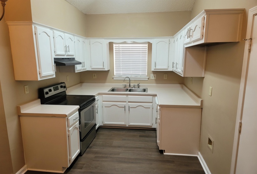U-shaped kitchen featuring white cabinetry, light-toned countertops, and wood-finish flooring