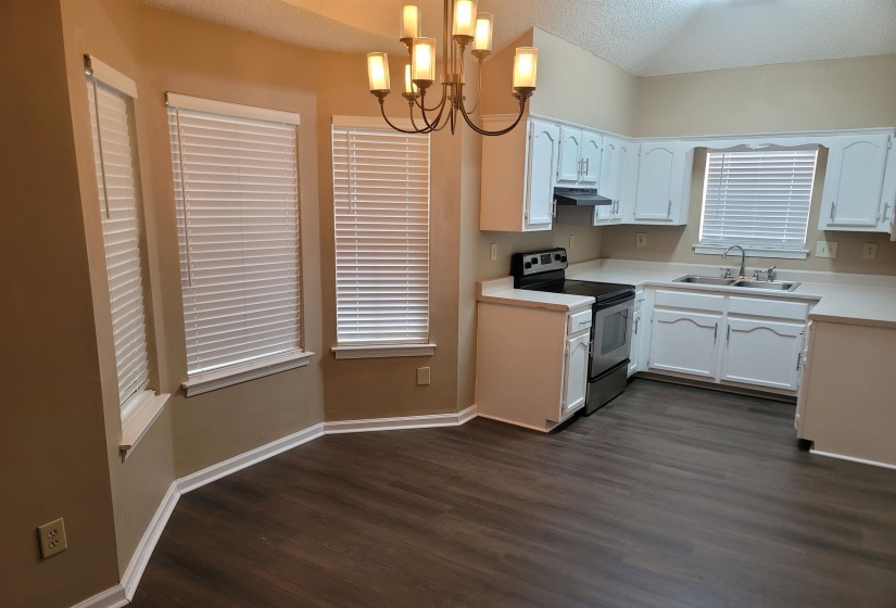Open-concept kitchen featuring white cabinetry, light countertops, and a stainless steel range