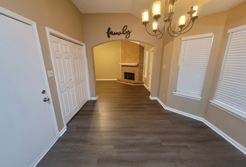 Spacious interior featuring wood-finish flooring, an arched doorway, and a brick fireplace