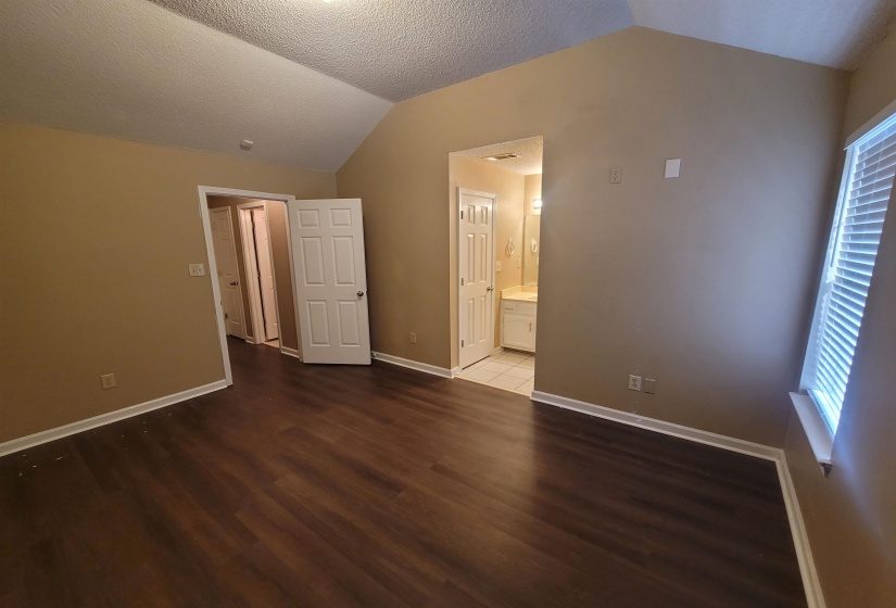 Spacious room featuring vaulted ceilings, wood-finish flooring, and neutral wall tones