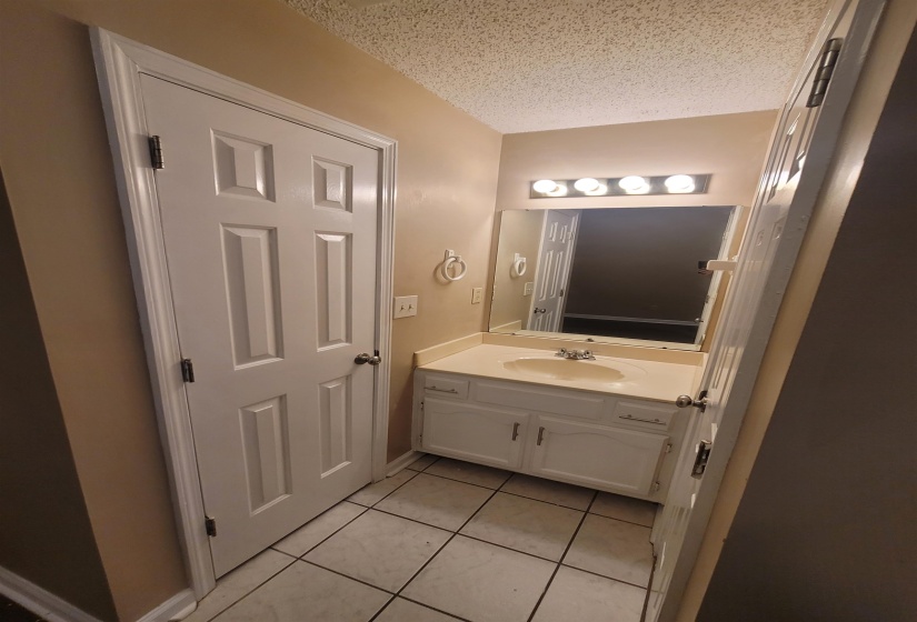 Bathroom vanity featuring a white cabinet, integrated sink, and mounted mirror