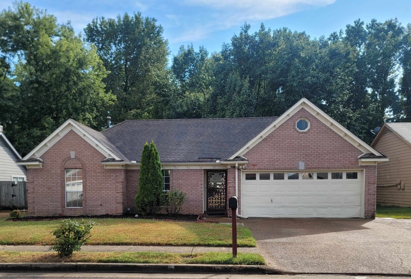 Brick facade residence featuring a dark shingle roof and a two-car garage