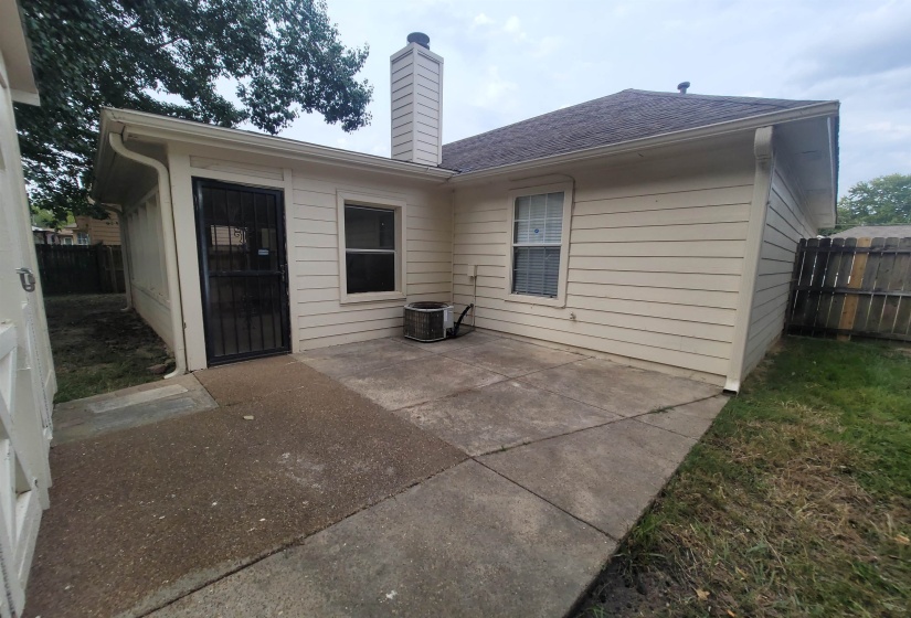 Rear exterior featuring horizontal siding, a security screen door, and a concrete patio