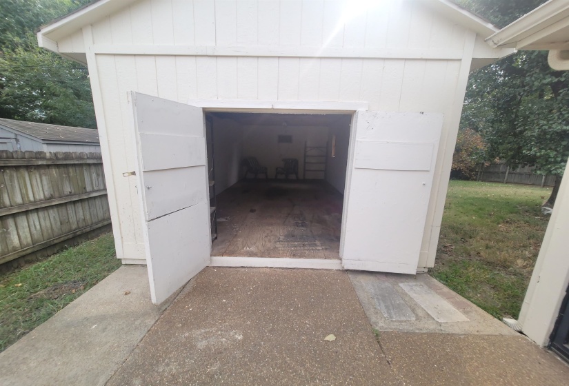 Detached storage structure featuring white panel siding and a gabled roofline