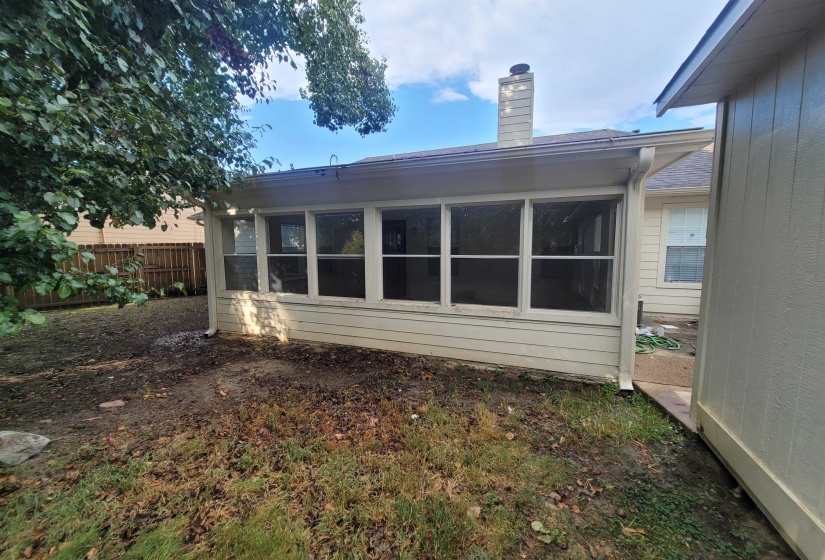 Rear exterior featuring a screened-in porch with multiple window panels, horizontal siding, and a prominent chimney