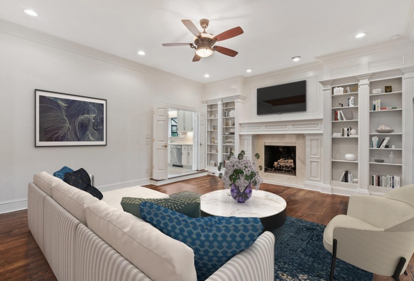 Spacious living area featuring rich wood-finish flooring, a decorative fireplace with a stone surround, and extensive built-in shelving