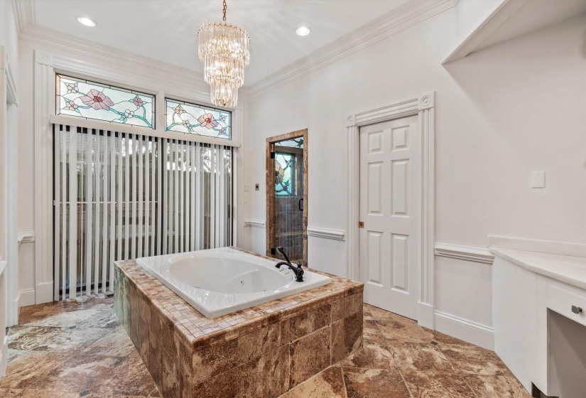 Soaking tub with a tiled surround, complemented by stained glass transom windows