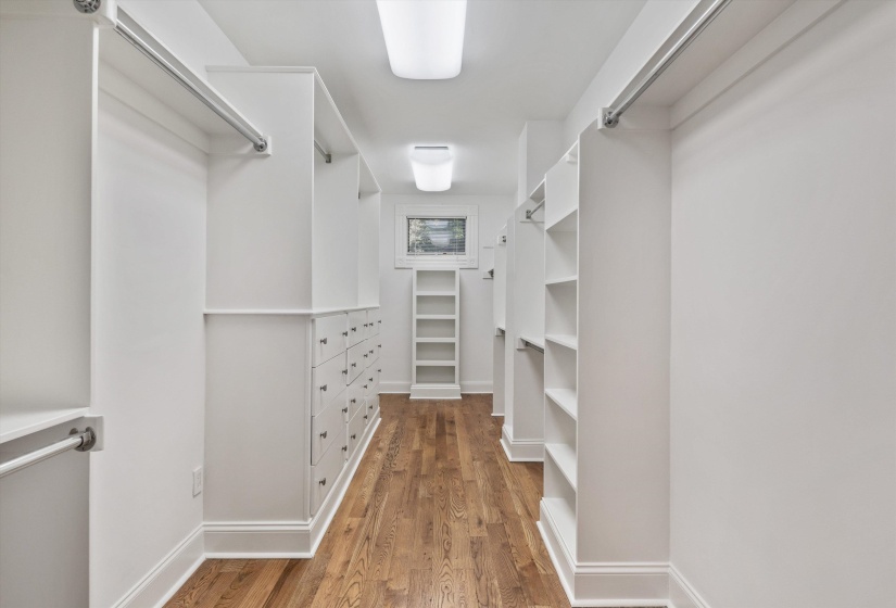 Walk-through closet featuring wood-finish flooring, built-in shelving, integrated hanging rods, extensive drawer storage, and window light