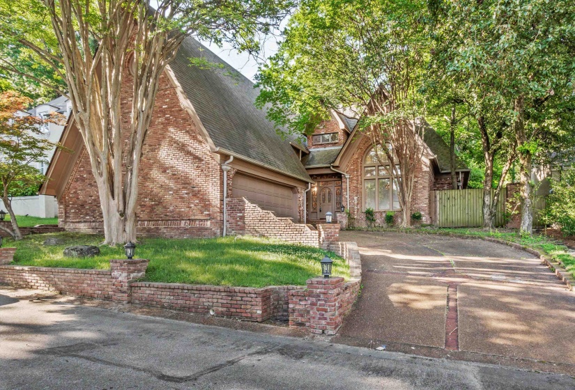 Brick exterior residence with a prominent arched window, a two-car garage, and a brick-lined driveway