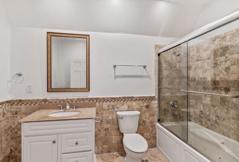 Bathroom featuring a white vanity with a granite countertop, undermount sink, and a framed mirror