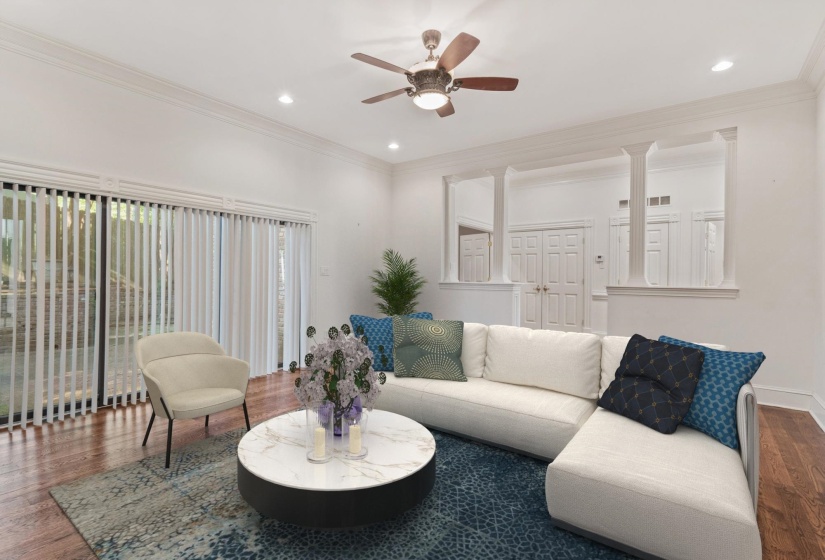 Spacious living area featuring rich wood-finish flooring, a contemporary ceiling fan, recessed lighting, and crown molding