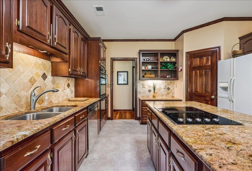 Kitchen featuring rich wood cabinetry, stone countertops, stainless steel appliances, and a tile backsplash