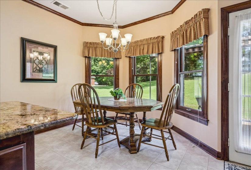 Dining nook featuring a multi-paned window array, chandelier lighting, tile flooring, and custom wood trim
