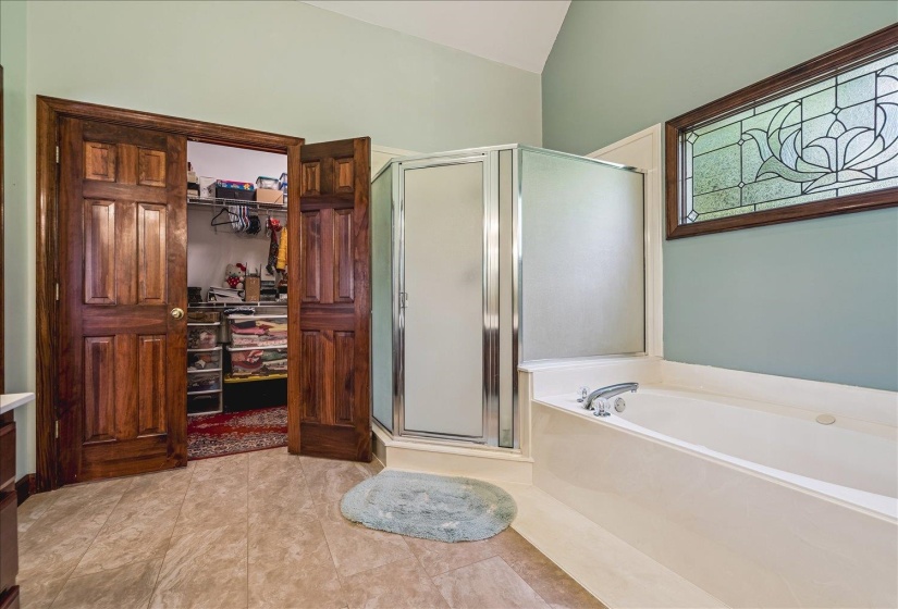 Bathroom featuring a built-in tub, separate shower enclosure with frosted glass, and a decorative stained glass window