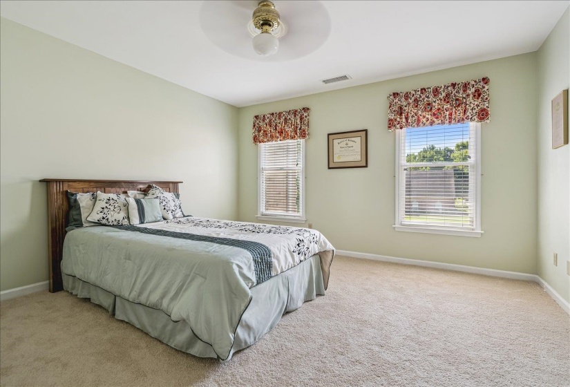 Light-filled room featuring two windows with blinds, a ceiling fan, and neutral carpeting