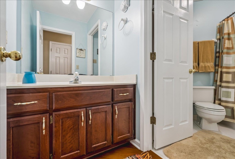 Vanity featuring a white countertop, chrome faucet, and wood-finish cabinetry with decorative hardware