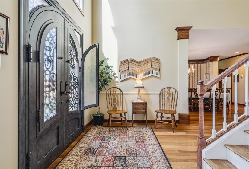 Grand entryway featuring double doors with decorative wrought iron and arched glass inserts
