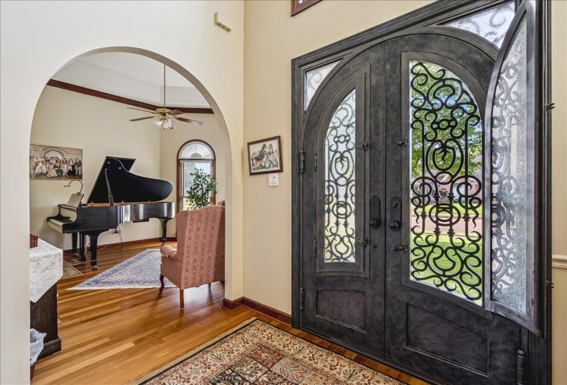 Grand entryway featuring decorative wrought iron double doors with glass inserts