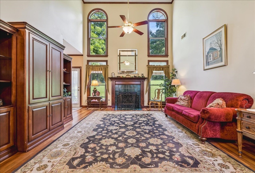 Vaulted living area featuring high ceilings, wood-finish flooring, and a decorative fireplace with a tile surround