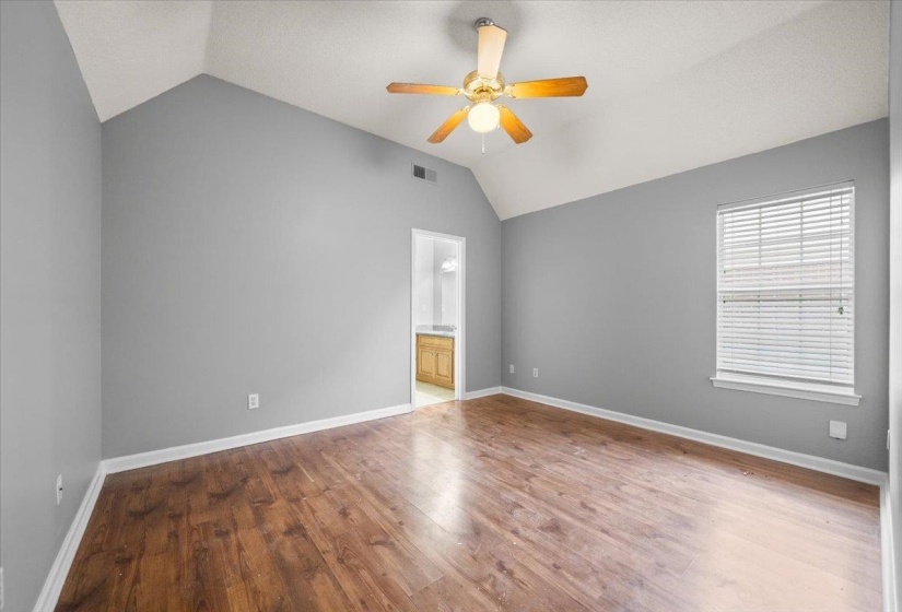 Vaulted ceiling room with wood-finish flooring, a ceiling fan, and a window with blinds
