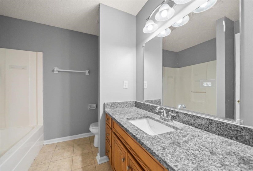 Bathroom featuring a spacious vanity with granite-style countertop, integrated sink, and wood-finish cabinetry