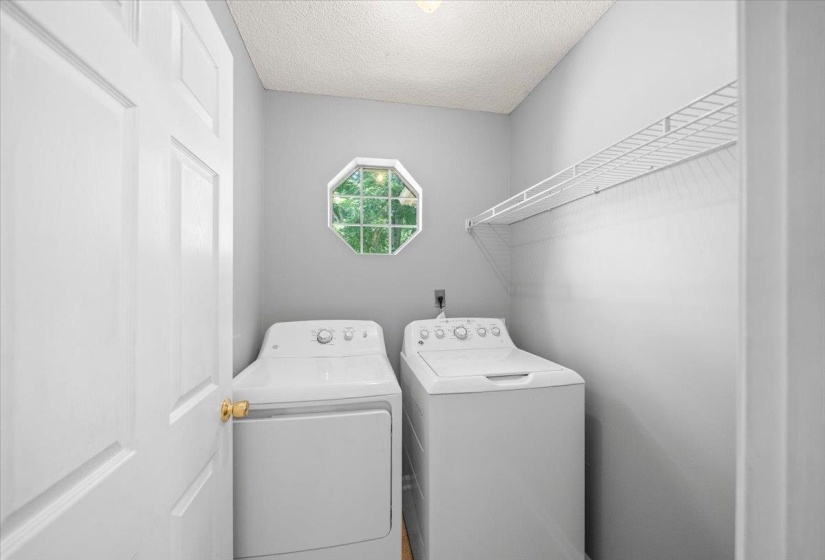 Dedicated laundry area featuring a white paneled door, an octagonal window, and a white wire shelf