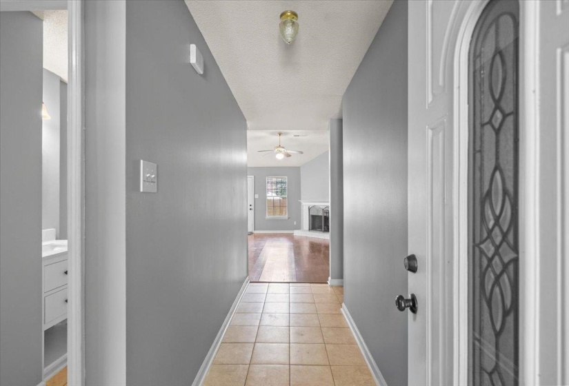 Entryway featuring neutral wall tones, decorative glass panel front door, and tile flooring