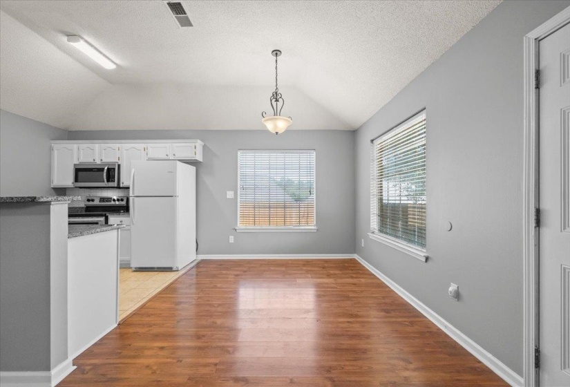 Open-concept living space featuring wood-finish flooring, vaulted ceilings, and gray wall tones