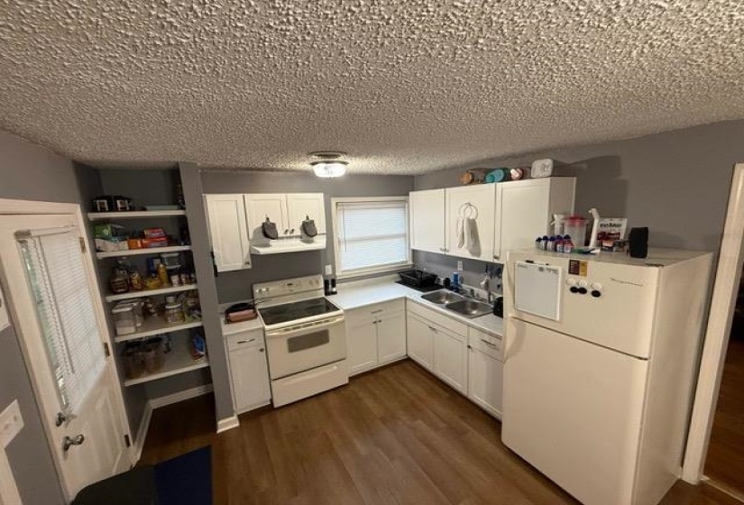 Kitchen featuring wood-finish flooring and white cabinetry