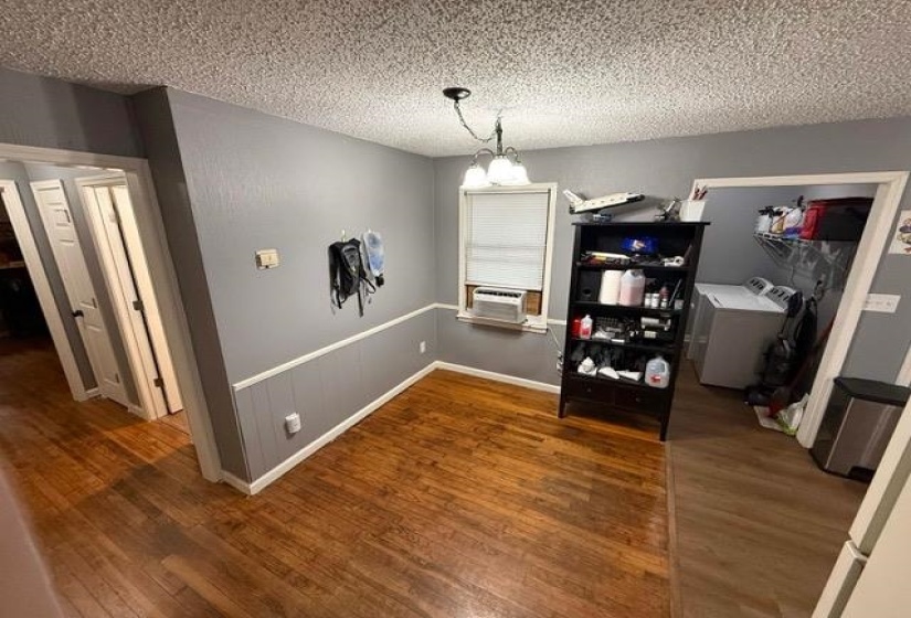 Dining area featuring wood-finish flooring, two-tone wall paneling, and a window with blinds
