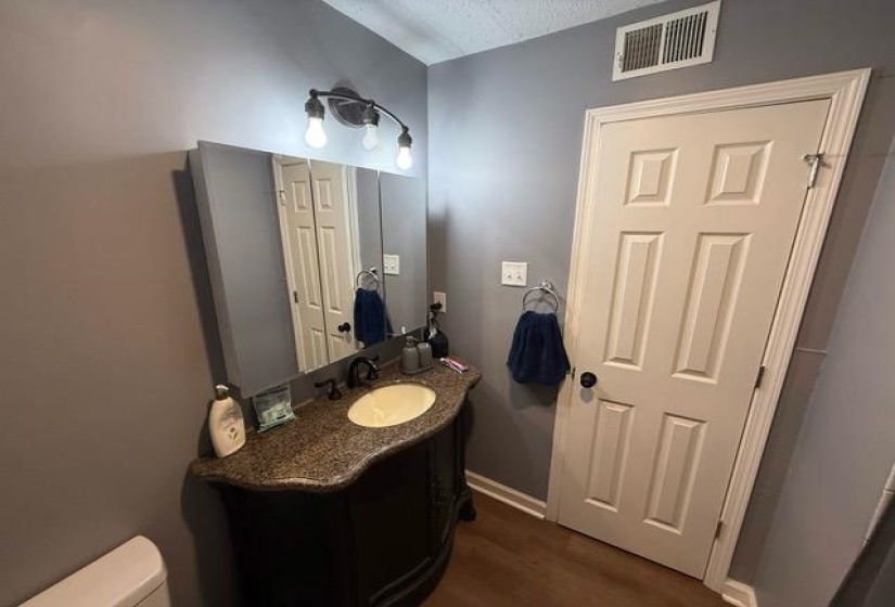 Vanity featuring a dark wood-finish cabinet with curved details, a speckled countertop, and an oval undermount sink