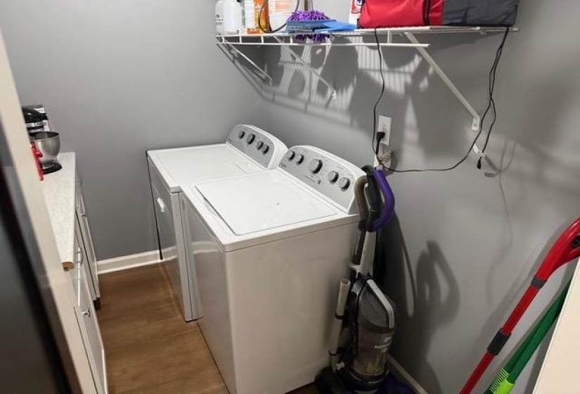 Dedicated laundry area featuring a washer and dryer, wood-finish flooring, built-in shelving, and light gray wall paint