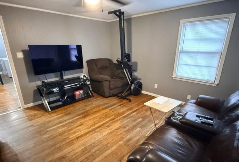 Living area with wood-finish flooring, light gray walls, and white trim