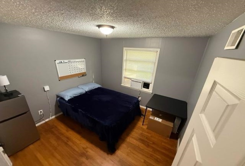 Room featuring wood-finish flooring, neutral gray walls, a window with blinds, and a ceiling-mounted light fixture