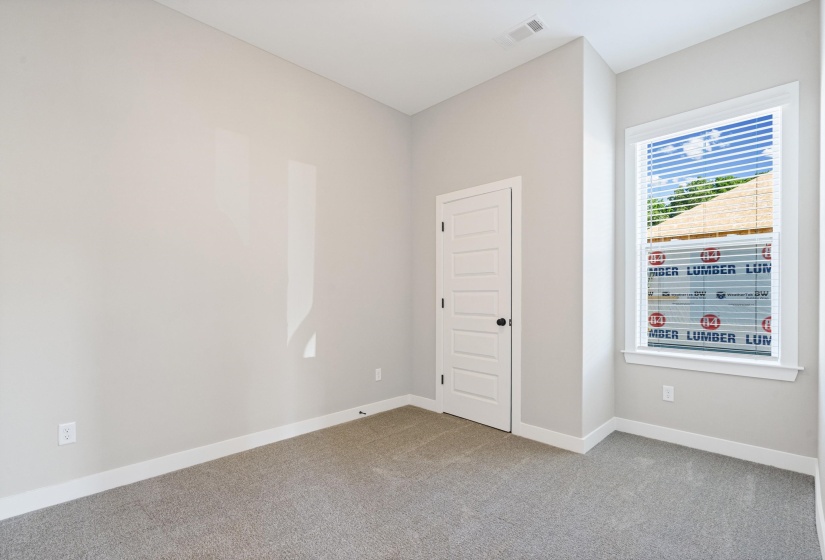 Carpeted room featuring light gray walls, white trim, and a white paneled door with a black knob