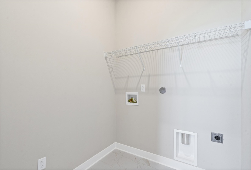 Utility space featuring a wire shelving unit, appliance hookups, and light-toned flooring