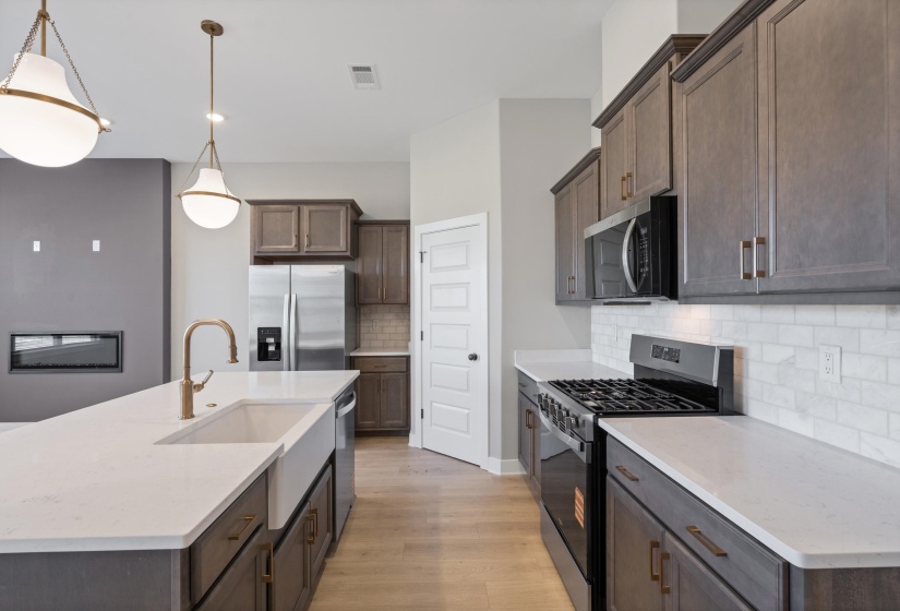 Kitchen featuring dark wood cabinetry, light wood-finish flooring, white countertops, and a subway tile backsplash